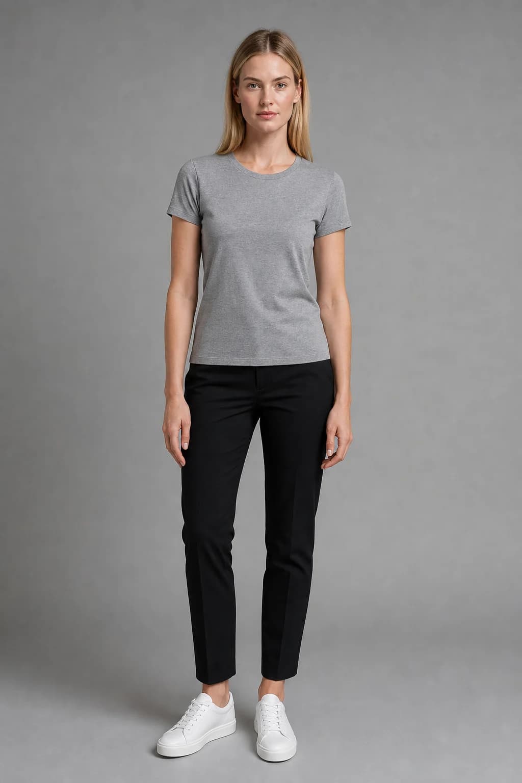 House model reference: a blonde woman in a grey T-shirt, black trousers and white trainers against a grey wall